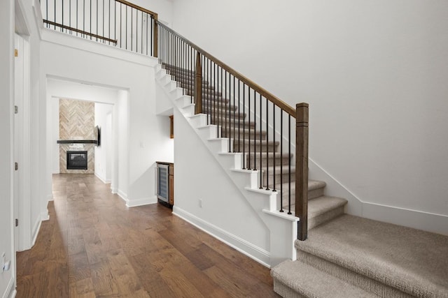 stairs featuring a high ceiling, wood-type flooring, and a fireplace