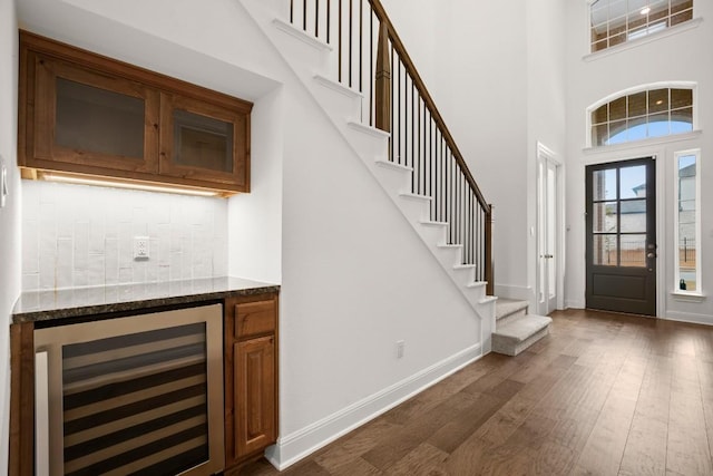 entryway featuring wine cooler, dark wood-type flooring, indoor bar, and a high ceiling