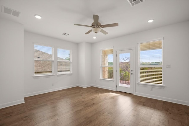 unfurnished room with a wealth of natural light, dark hardwood / wood-style floors, and ceiling fan