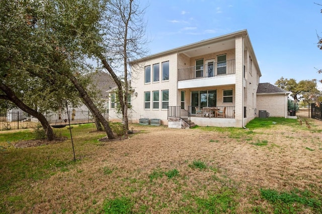 rear view of property featuring central AC unit, a yard, and a balcony