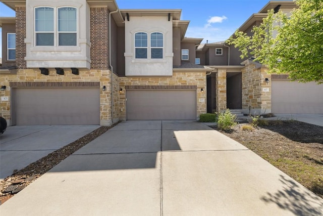 multi unit property with driveway, stone siding, an attached garage, and stucco siding