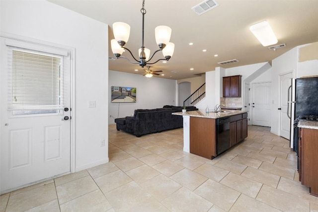 kitchen featuring dishwasher, sink, hanging light fixtures, light stone countertops, and a center island with sink