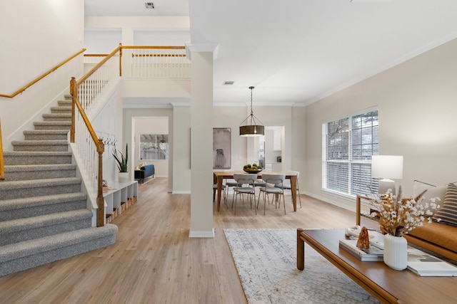 living room featuring ornamental molding, a healthy amount of sunlight, and light hardwood / wood-style floors