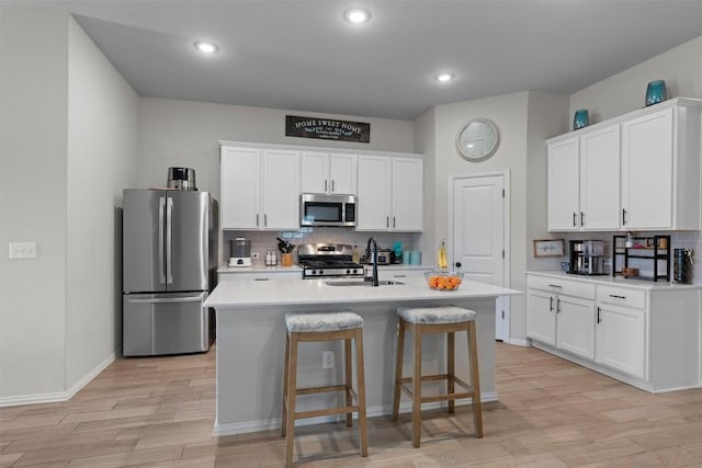 kitchen with white cabinetry, appliances with stainless steel finishes, a kitchen island with sink, and sink