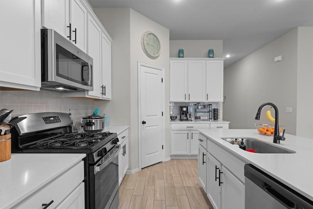 kitchen with sink, white cabinetry, backsplash, stainless steel appliances, and light hardwood / wood-style floors