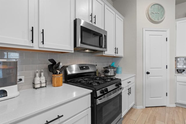 kitchen featuring stainless steel appliances, light hardwood / wood-style flooring, decorative backsplash, and white cabinets