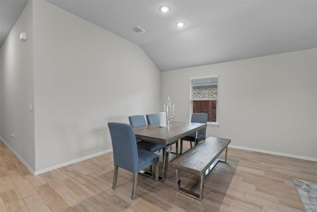 dining space with vaulted ceiling and light hardwood / wood-style flooring