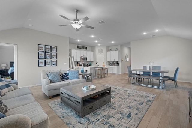 living room with ceiling fan, lofted ceiling, and light wood-type flooring