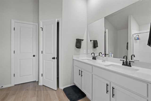 bathroom featuring wood-type flooring, a shower with shower door, and vanity