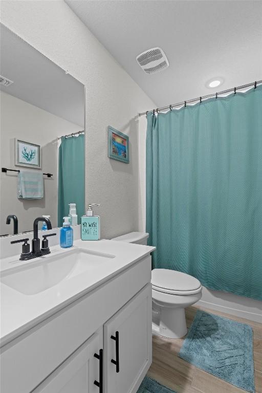 full bathroom featuring vanity, hardwood / wood-style floors, shower / tub combo, and toilet