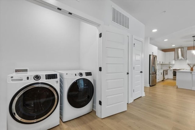 clothes washing area featuring independent washer and dryer and light wood-type flooring