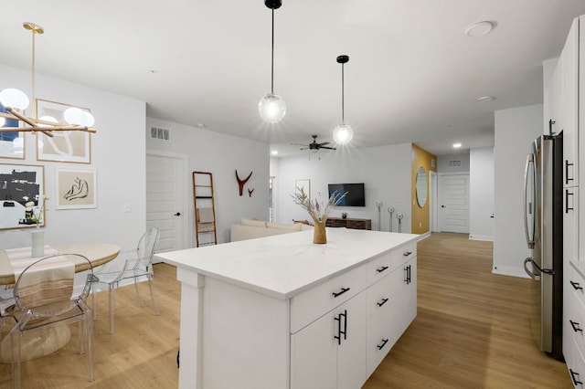 3101 Govalle Ave Unit 106, Austin, TX 78702 - kitchen with light wood-style floors, ceiling fan with notable chandelier, freestanding refrigerator, open floor plan, and a kitchen island