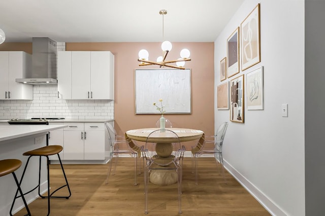 3101 Govalle Ave Unit 106, Austin, TX 78702 - kitchen with an inviting chandelier, light countertops, wall chimney exhaust hood, white cabinetry, and tasteful backsplash