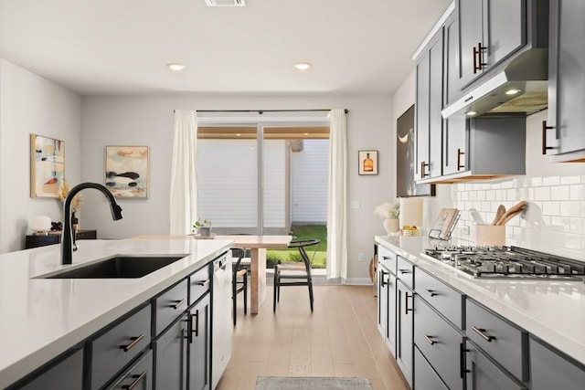 kitchen featuring stainless steel gas cooktop, sink, gray cabinetry, dishwasher, and backsplash