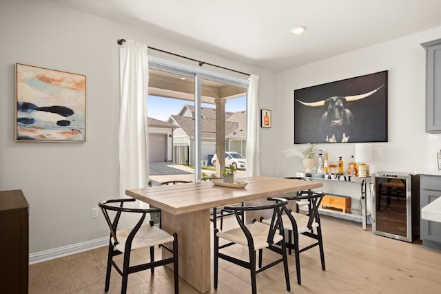 dining area with wine cooler, light hardwood / wood-style flooring, and indoor bar