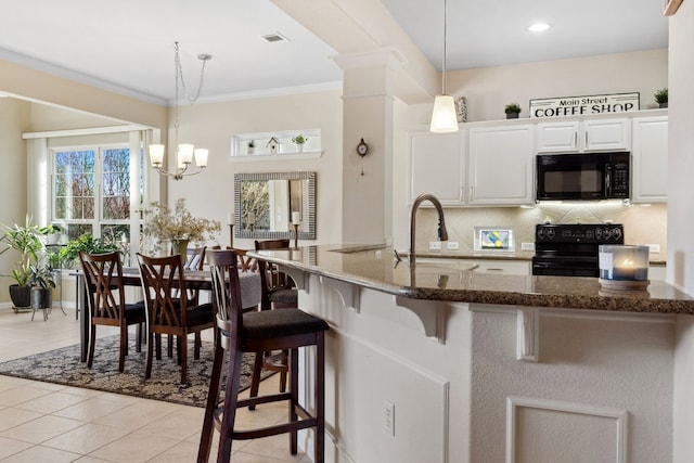 kitchen featuring pendant lighting, sink, white cabinetry, a kitchen breakfast bar, and black appliances