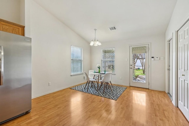 dining space featuring vaulted ceiling, a wealth of natural light, a notable chandelier, and light wood-type flooring