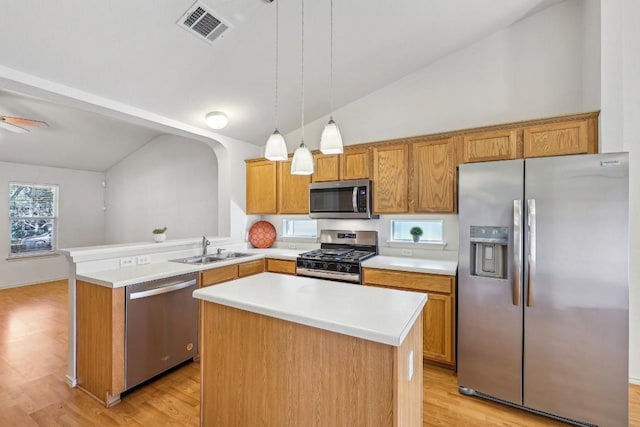 kitchen featuring appliances with stainless steel finishes, hanging light fixtures, sink, and a kitchen island