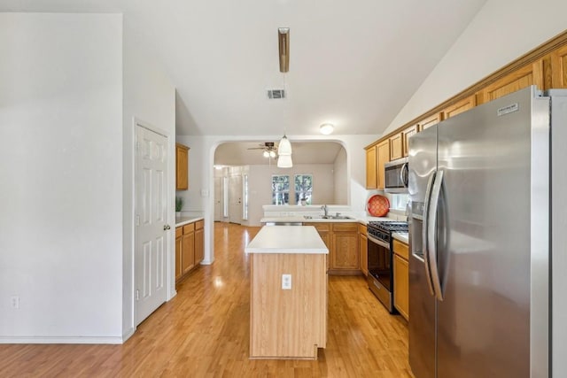 kitchen featuring a kitchen island, vaulted ceiling, appliances with stainless steel finishes, and decorative light fixtures