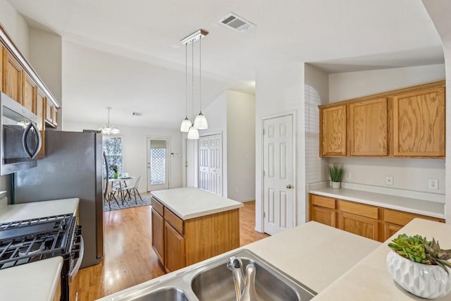 kitchen with pendant lighting, lofted ceiling, light hardwood / wood-style flooring, stainless steel appliances, and a center island