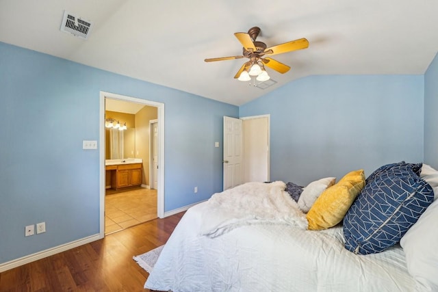 bedroom featuring hardwood / wood-style flooring, ceiling fan, connected bathroom, and vaulted ceiling