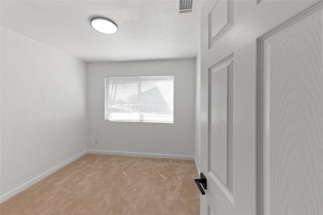 spare room with light colored carpet and a textured ceiling