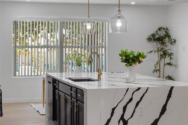 kitchen with sink, light hardwood / wood-style flooring, light stone counters, and decorative light fixtures