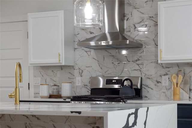 kitchen featuring white cabinetry, wall chimney range hood, stainless steel stove, and decorative backsplash