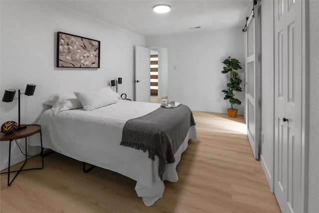 bedroom featuring a barn door and light hardwood / wood-style floors