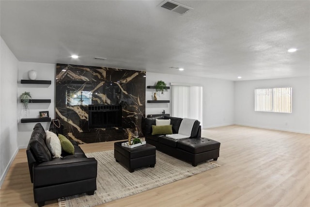 living room featuring a fireplace, light hardwood / wood-style flooring, and a textured ceiling