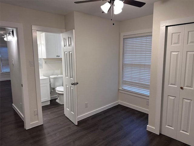 unfurnished bedroom with ceiling fan, ensuite bathroom, dark hardwood / wood-style floors, and a closet