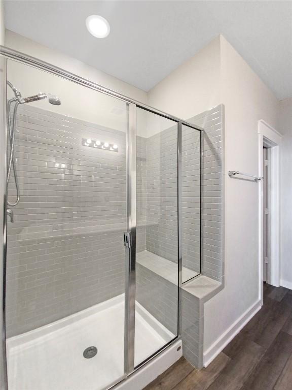 bathroom with a shower with shower door and hardwood / wood-style floors