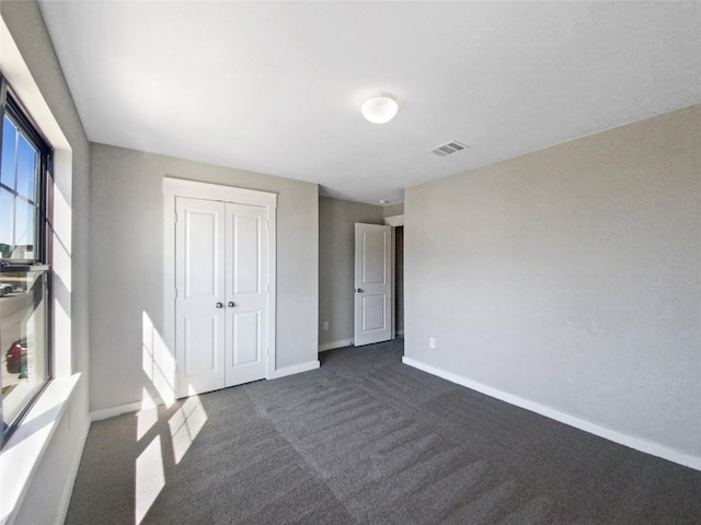 unfurnished bedroom with a closet and dark colored carpet