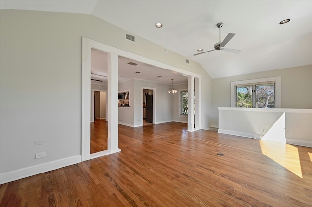 unfurnished living room with ceiling fan with notable chandelier, wood-type flooring, and vaulted ceiling