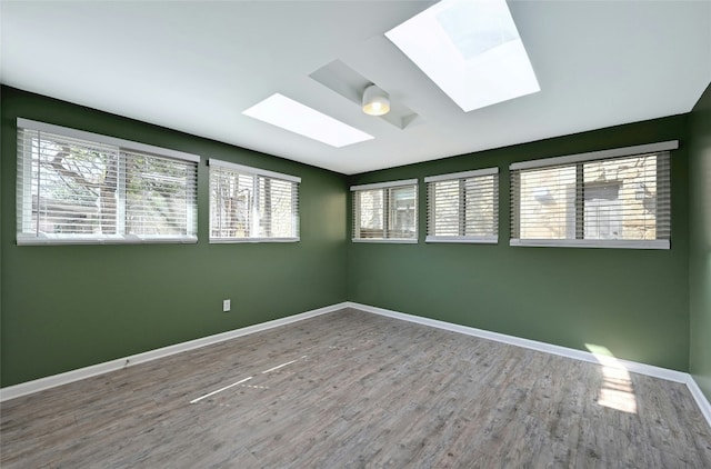 empty room featuring wood-type flooring and a skylight