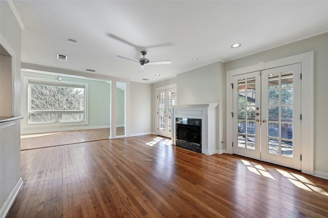 unfurnished living room featuring a wealth of natural light, a fireplace, french doors, and wood-type flooring