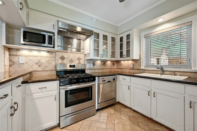 kitchen with sink, ornamental molding, white cabinets, stainless steel appliances, and wall chimney range hood