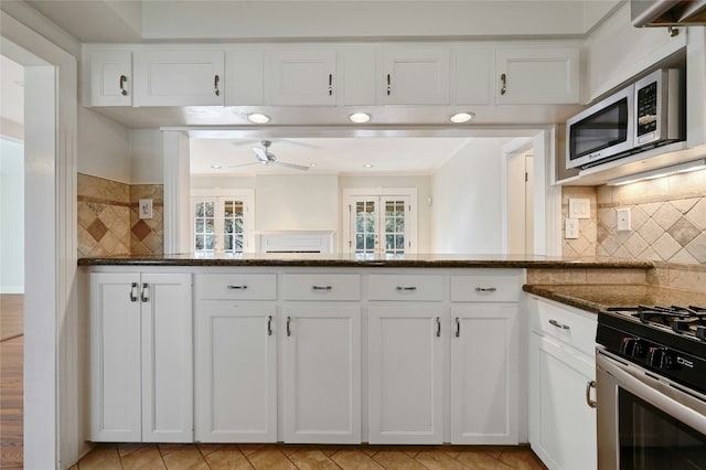 kitchen featuring stainless steel appliances, white cabinetry, and dark stone countertops