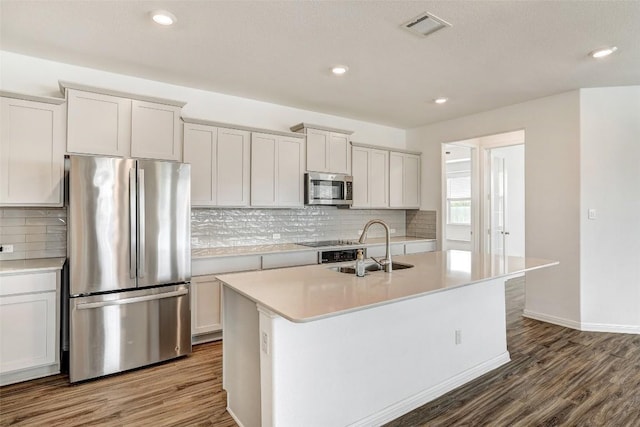 kitchen featuring appliances with stainless steel finishes, an island with sink, wood-type flooring, and white cabinets