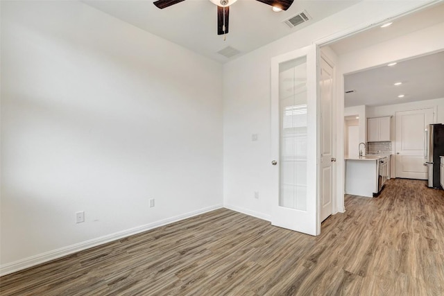 empty room with sink, ceiling fan, and light hardwood / wood-style flooring