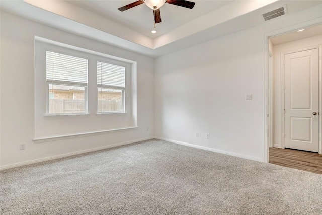 empty room featuring ceiling fan, carpet flooring, and a raised ceiling