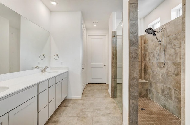 bathroom with vanity, a tile shower, and tile patterned floors