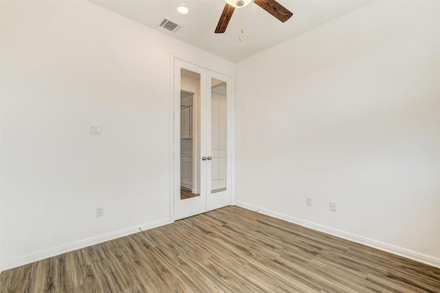 empty room with french doors, ceiling fan, and wood-type flooring