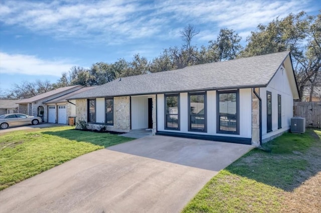 view of front of property featuring a garage, a front yard, and central AC unit