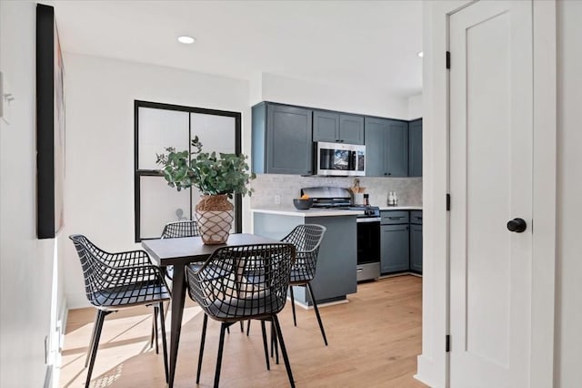 kitchen with backsplash, stainless steel appliances, and light wood-type flooring