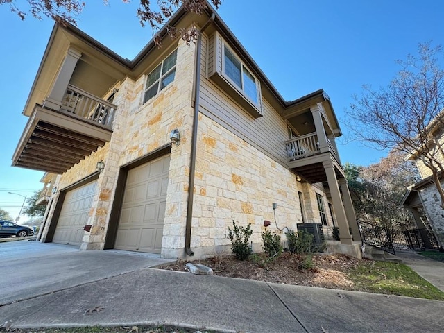 view of side of property featuring a garage, central AC, and a balcony