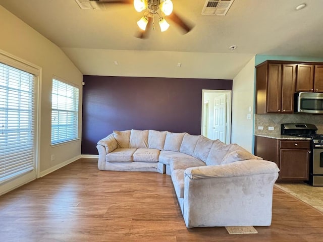 living room with vaulted ceiling, ceiling fan, and light wood-type flooring