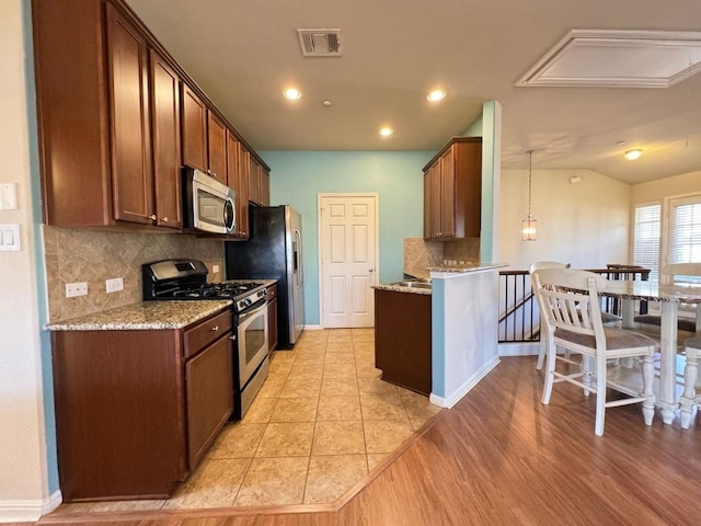 kitchen with stainless steel appliances, light stone countertops, hanging light fixtures, and vaulted ceiling