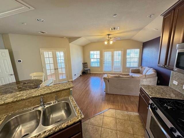 kitchen featuring light tile patterned flooring, stone countertops, lofted ceiling, sink, and french doors