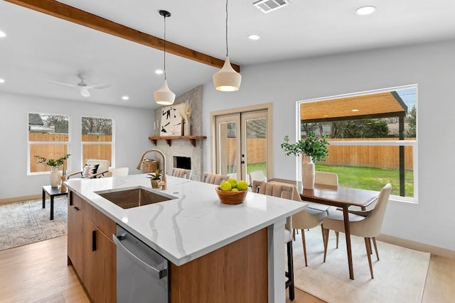 kitchen with a kitchen island with sink, dishwasher, sink, and hanging light fixtures